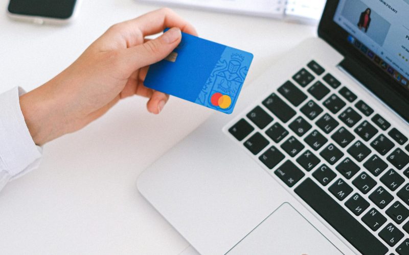 Person making an online purchase with a credit card on a laptop, showcasing modern ecommerce technology.